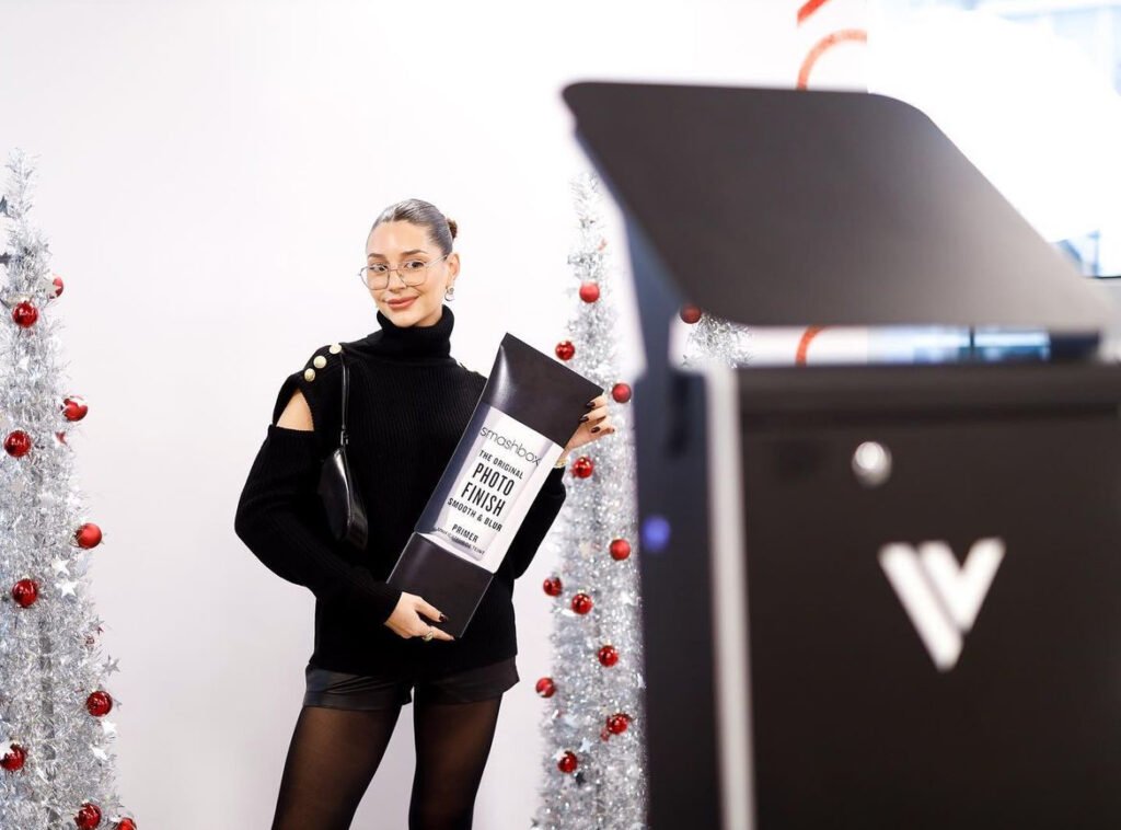 A smiling woman holding a product at an event with 360 video booth from Ineffable Views